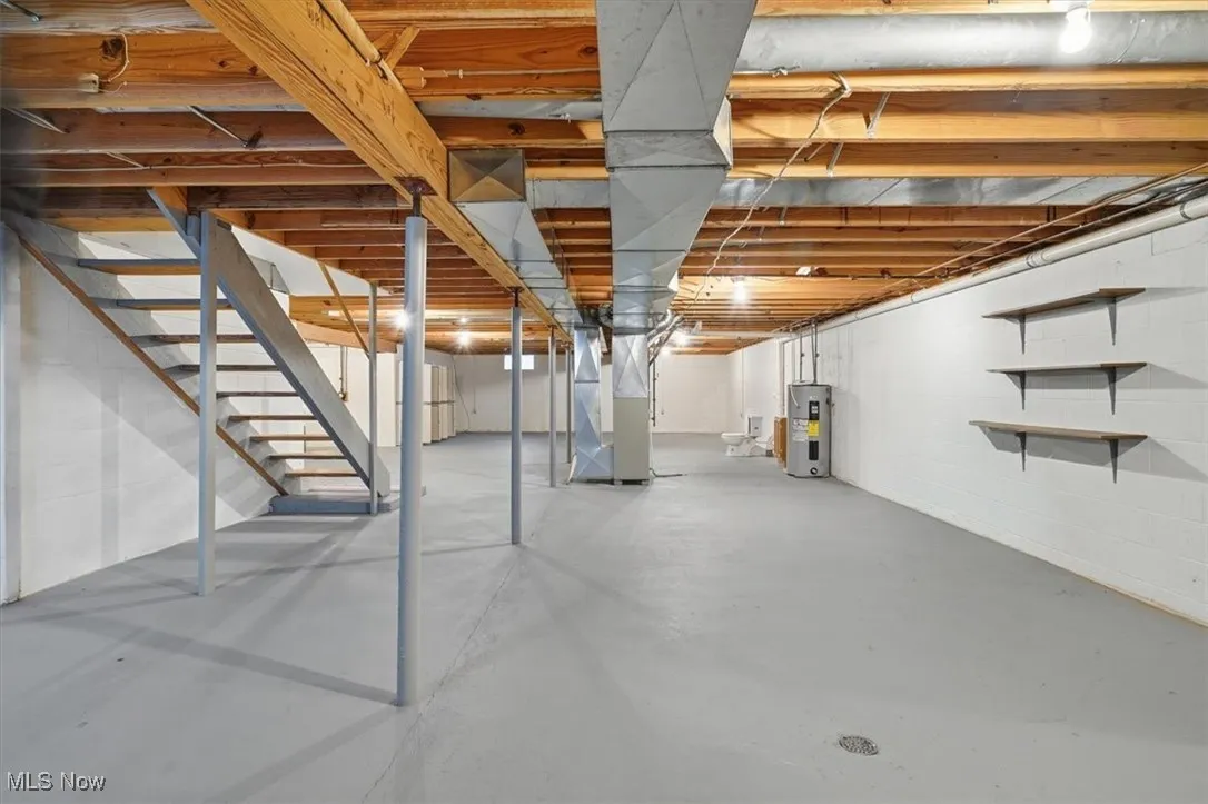 Unfinished basement featuring stairway, heating unit, and water heater