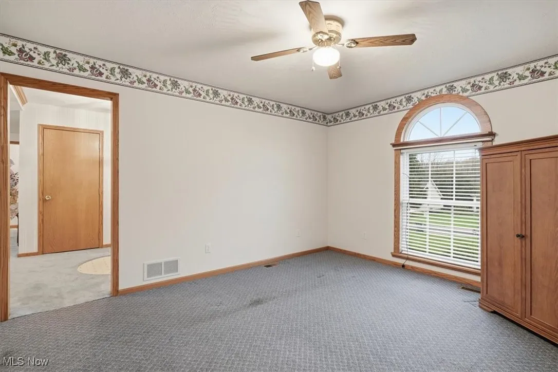 Carpeted empty room featuring ceiling fan and baseboards