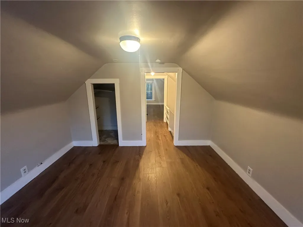 Bonus room with dark wood finished floors and lofted ceiling