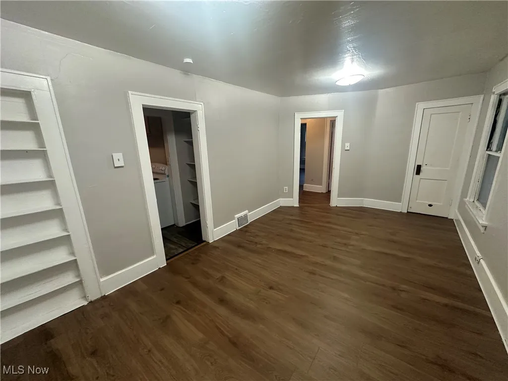 Empty room featuring dark wood-style floors and baseboards