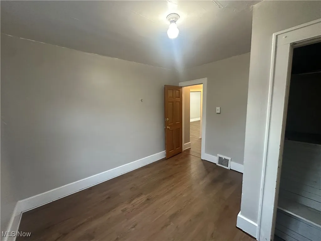 Unfurnished bedroom featuring dark wood-style floors and a closet
