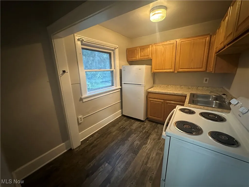 Kitchen featuring white appliances, light countertops, and dark wood-style floors