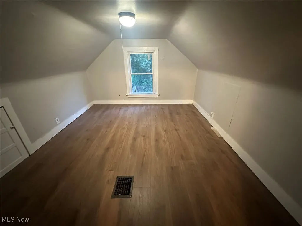 Additional living space featuring lofted ceiling and dark wood-type flooring