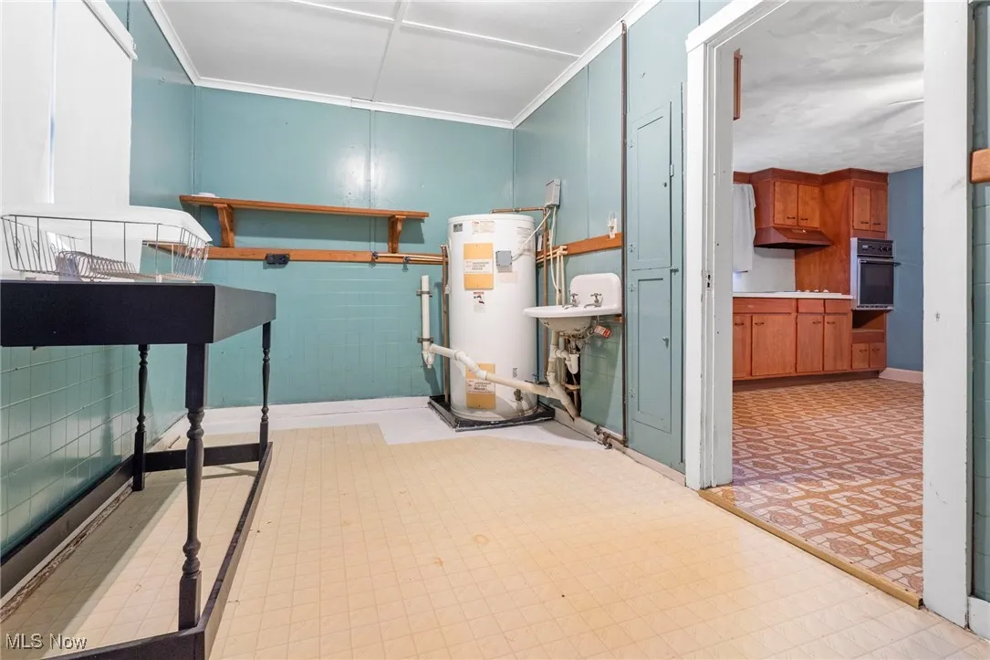 Bedroom with light floors, ornamental molding, and water heater