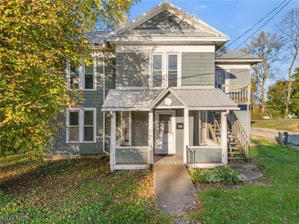 View of front facade featuring covered porch, a metal roof, and a front lawn