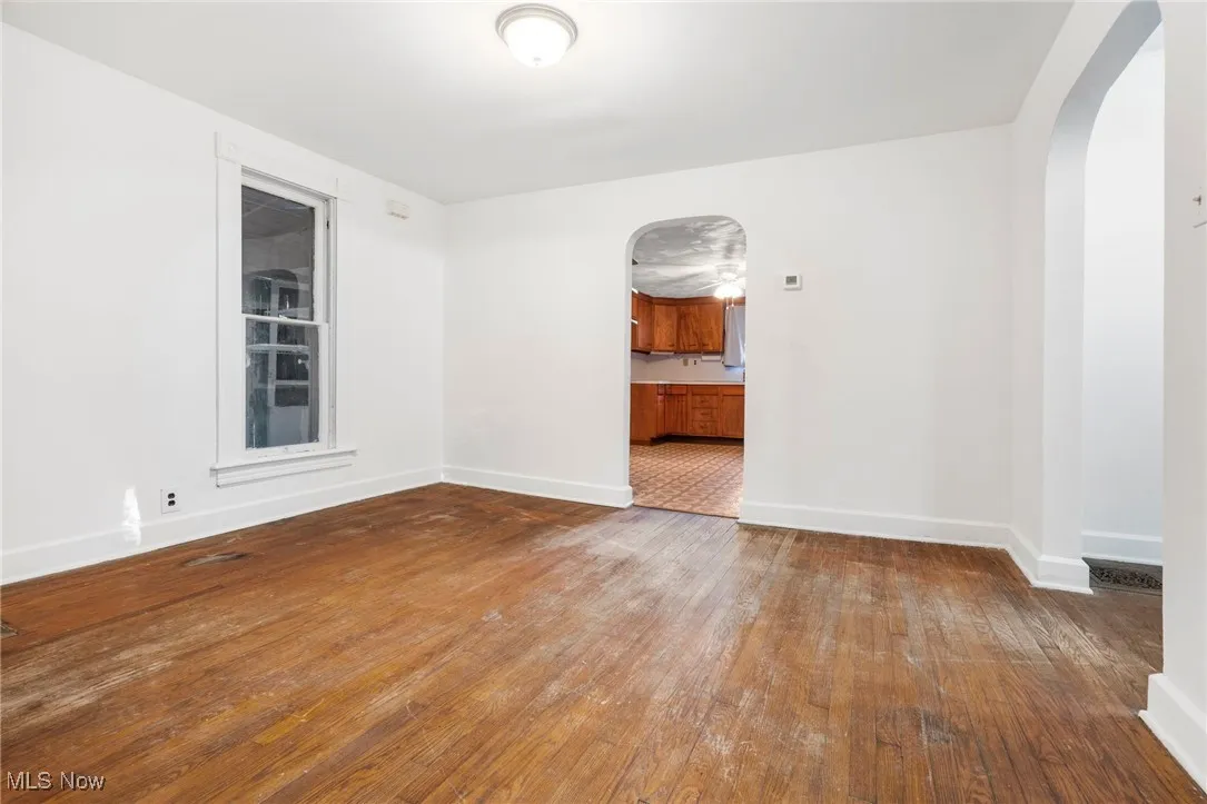 Empty room featuring arched walkways and hardwood / wood-style floors