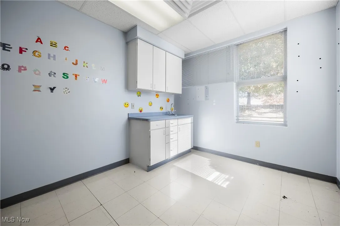 Kitchen featuring white cabinetry, a drop ceiling, and light countertops