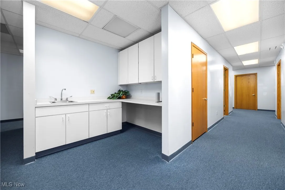 Bathroom featuring a paneled ceiling, dark carpet, and vanity