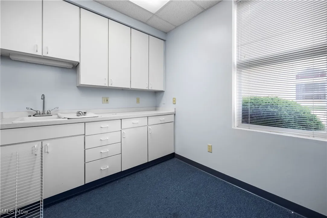 Kitchen featuring light countertops, white cabinets, and a drop ceiling