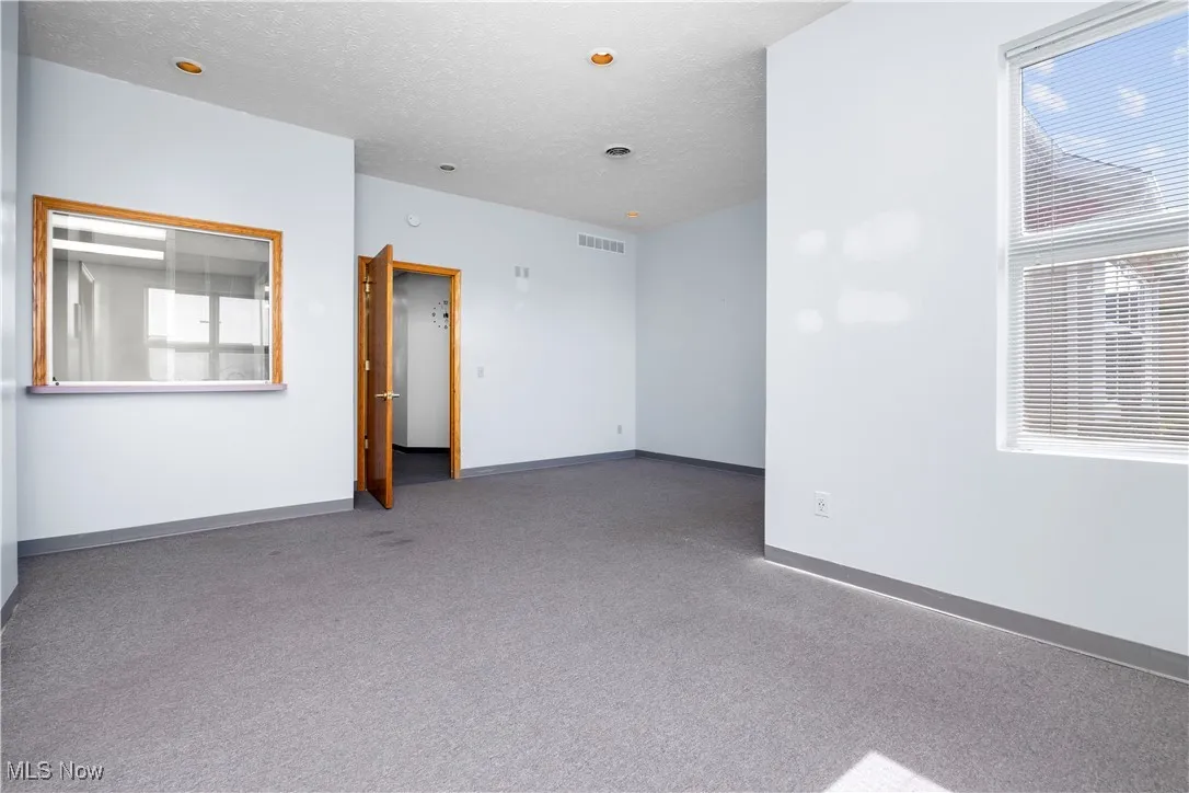 Carpeted empty room featuring baseboards and a textured ceiling