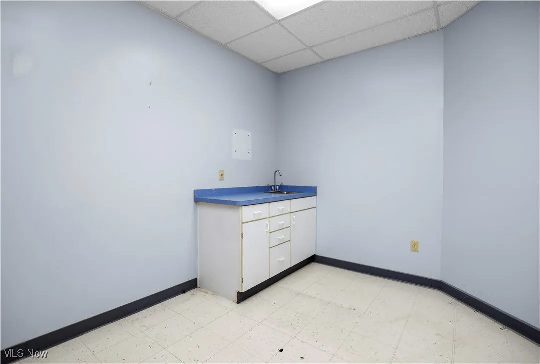 Laundry room with light flooring and a drop ceiling