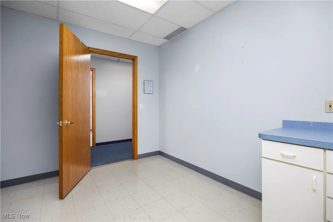 Empty room featuring light floors and a drop ceiling