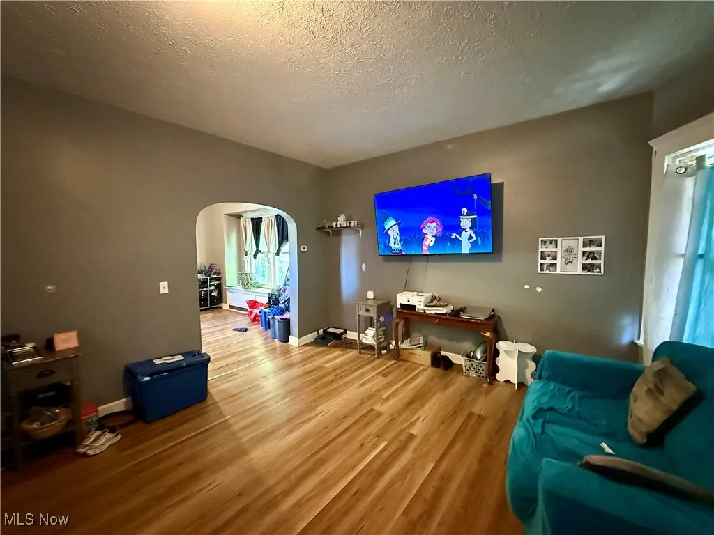 Living room with arched walkways, wood finished floors, and a textured ceiling