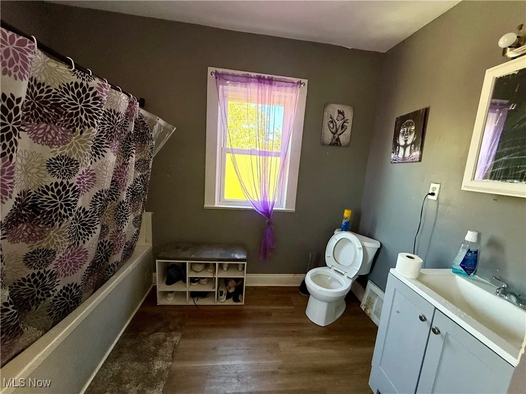 Full bath featuring vanity, dark wood-type flooring, and shower / bath combination with curtain
