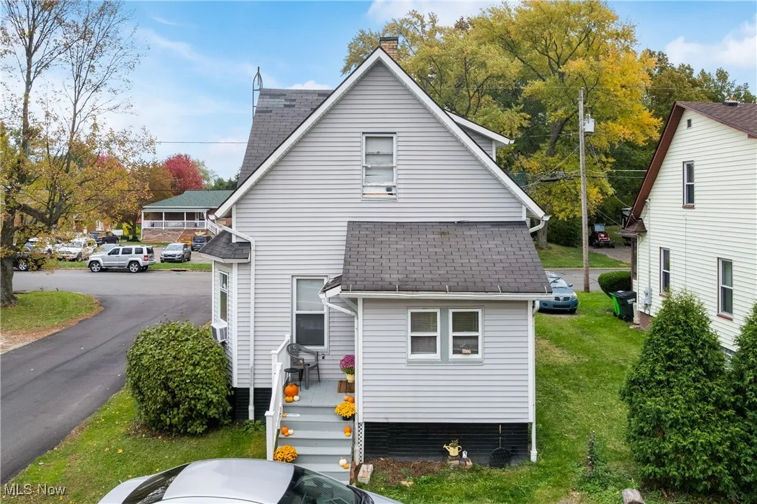 Rear view of property with a shingled roof, a chimney, and a lawn
