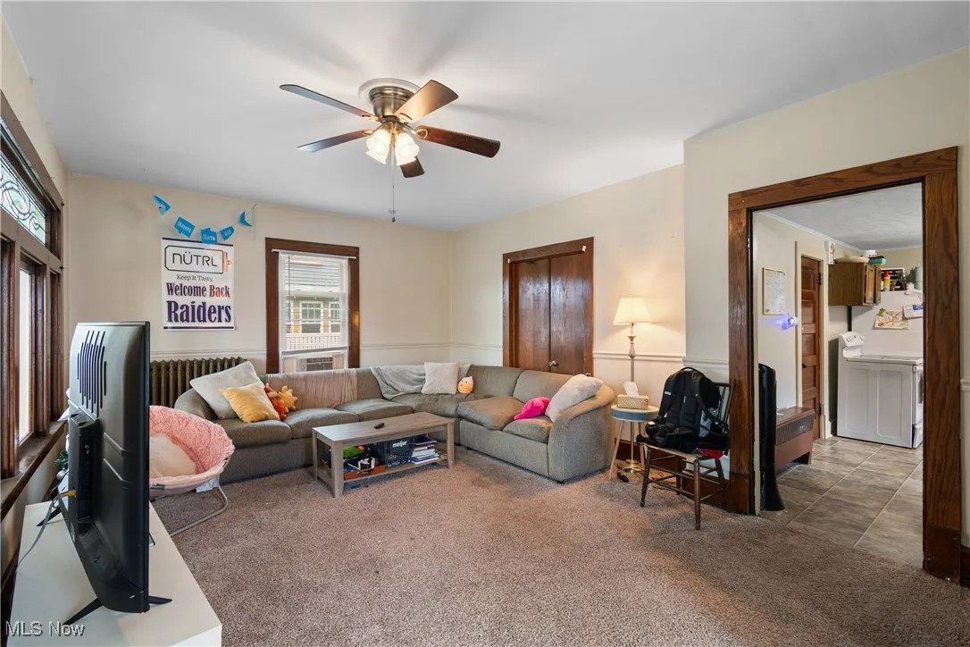 Living room with carpet floors, radiator heating unit, and ceiling fan