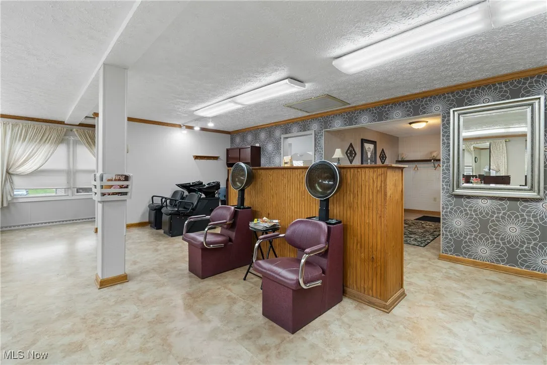 Living area with ornamental molding, wallpapered walls, and a textured ceiling