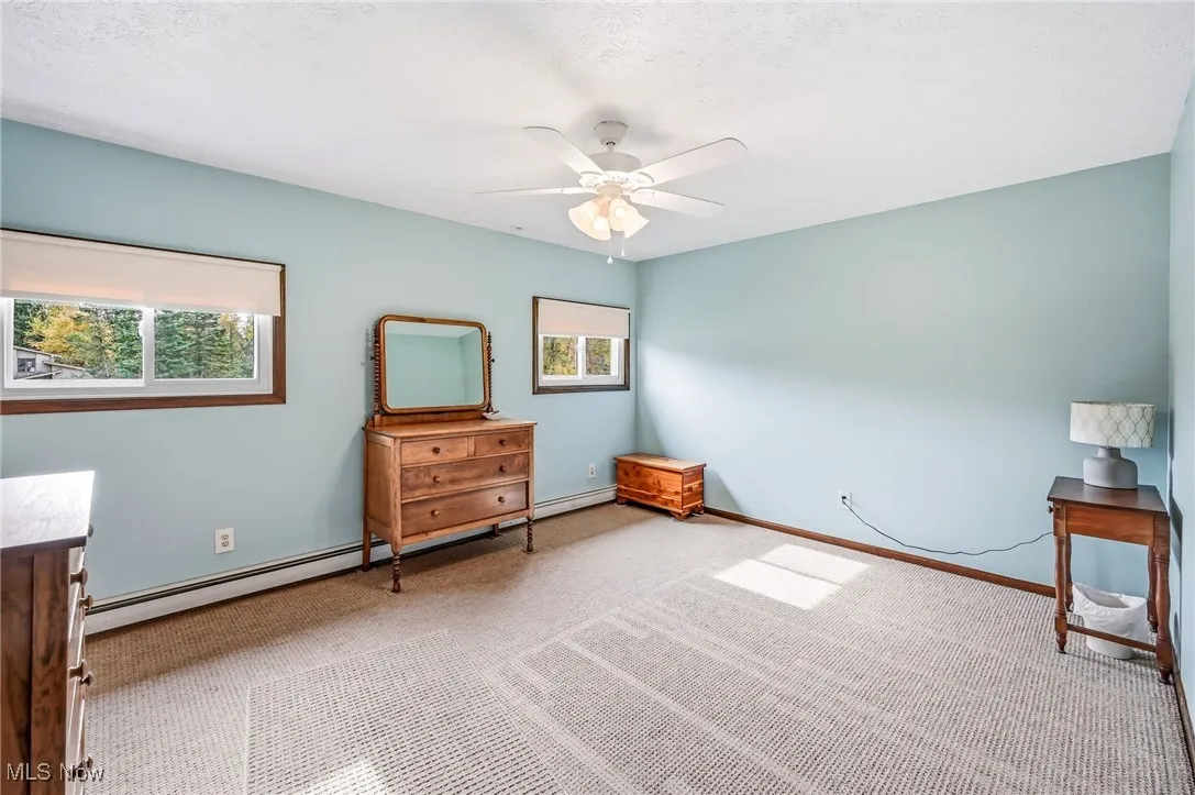 Bedroom with carpet floors, a textured ceiling, a baseboard heating unit, and ceiling fan