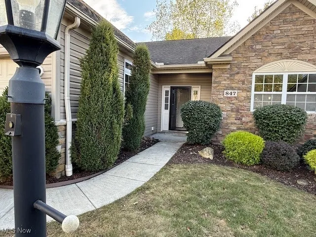 Entrance to property featuring stone siding and a yard