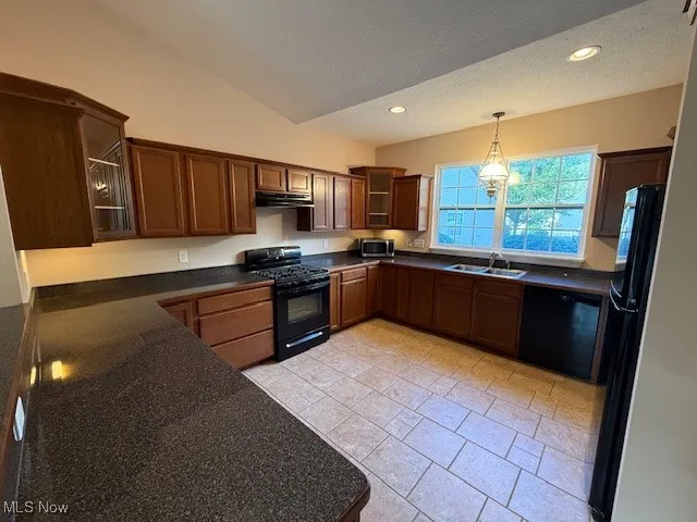Kitchen featuring glass insert cabinets, a textured ceiling, black appliances, decorative light fixtures, and recessed lighting