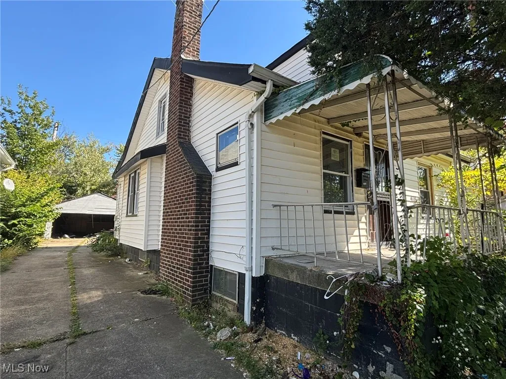 View of side of home with a chimney, a garage, and covered porch