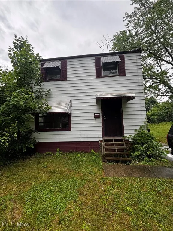 Traditional-style home with entry steps and a front lawn