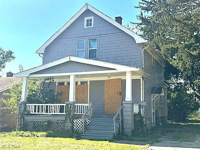 View of front of house with covered porch, a chimney, and a front yard