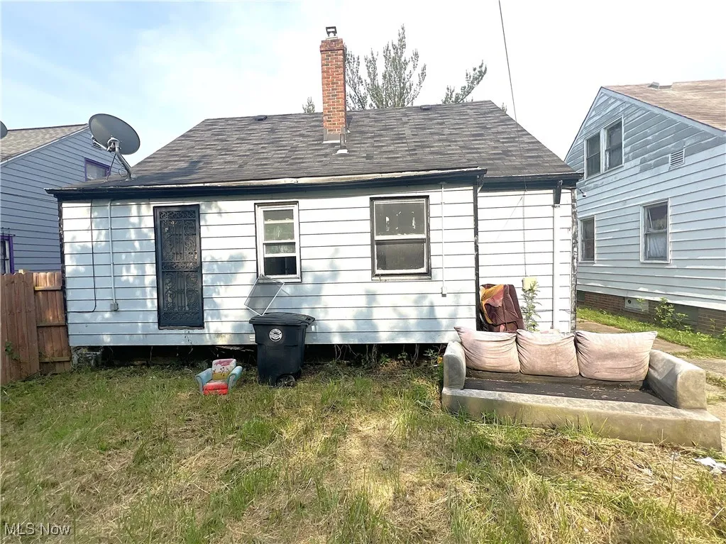 Back of property with a shingled roof and a chimney