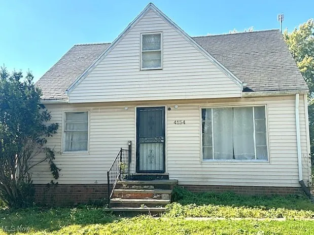 View of front of property featuring a front lawn and a shingled roof
