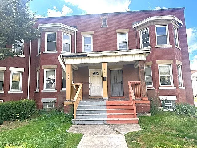 View of front of house featuring a porch, brick siding, and a front yard