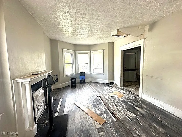 Unfurnished living room with hardwood / wood-style flooring, a textured ceiling, and a fireplace