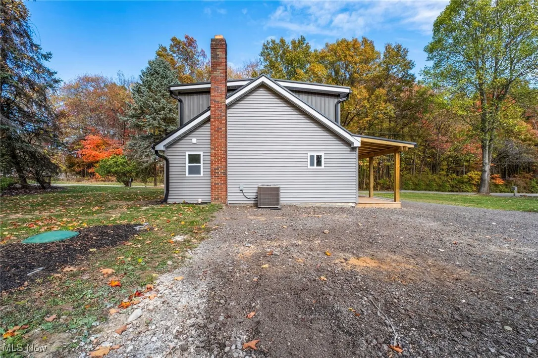 View of home's exterior with a chimney and a wooded view