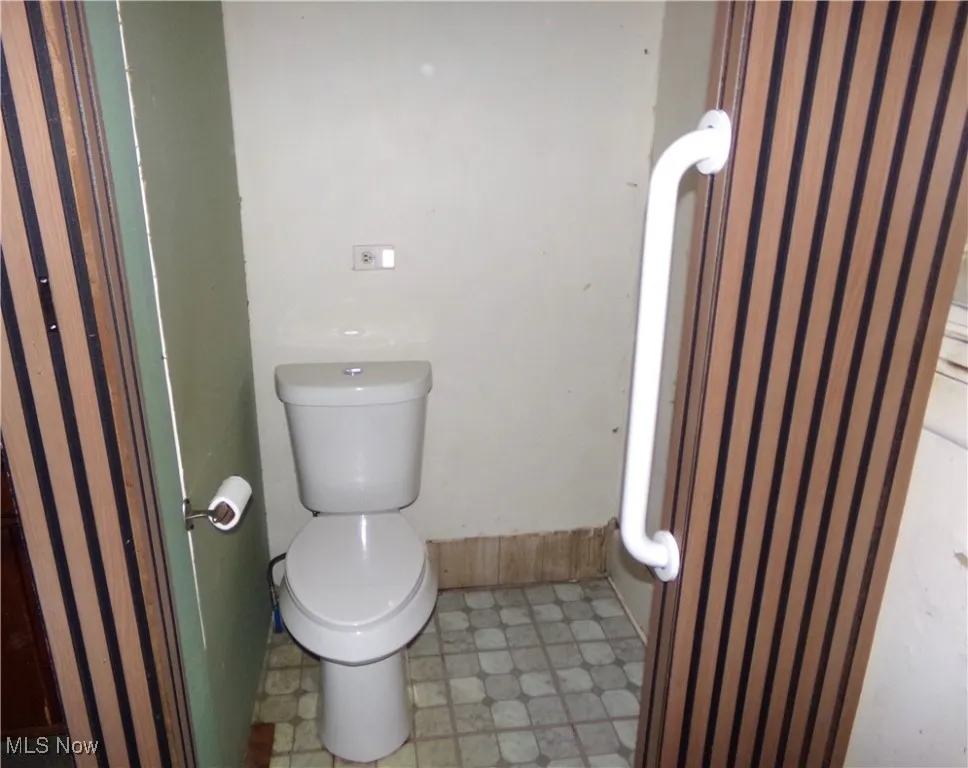 Half bathroom with toilet and light floors
