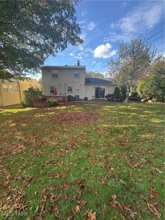 Rear view of house with a yard, a chimney, and a deck