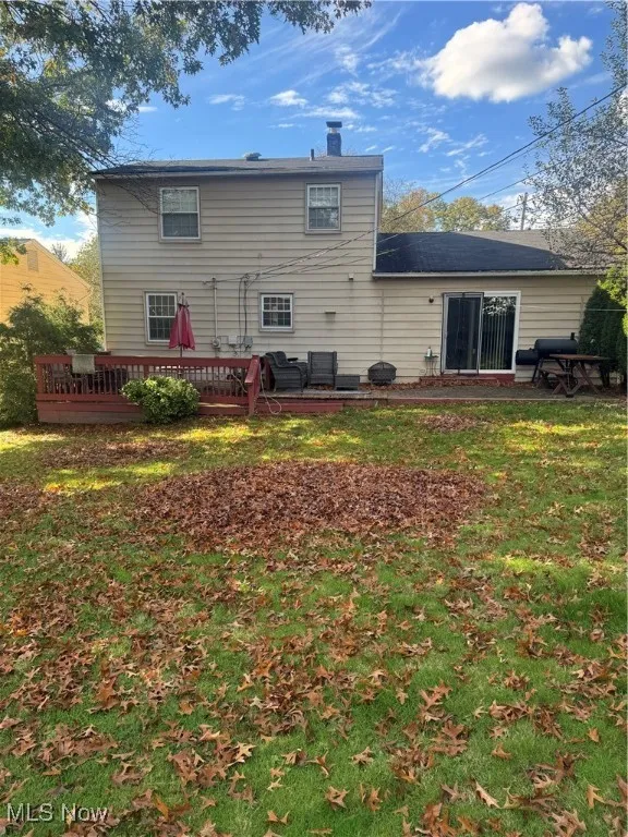 Back of house with a yard, a wooden deck, and a chimney