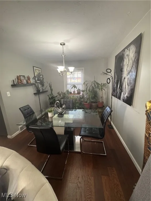 Dining area with dark wood-type flooring and a chandelier