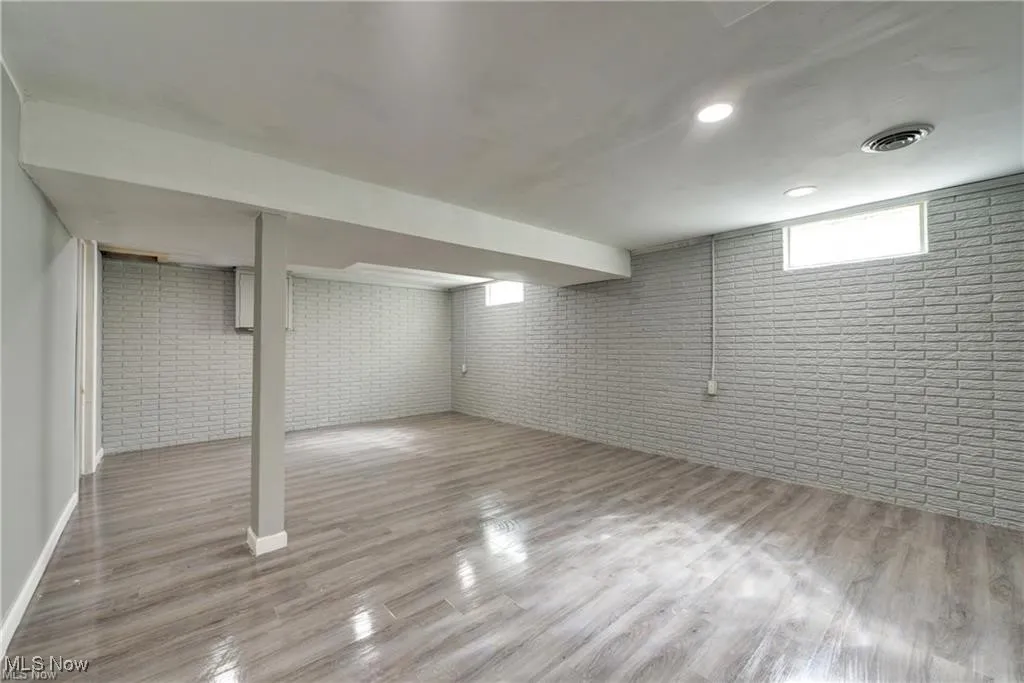 Below grade area with brick wall and light wood finished floors