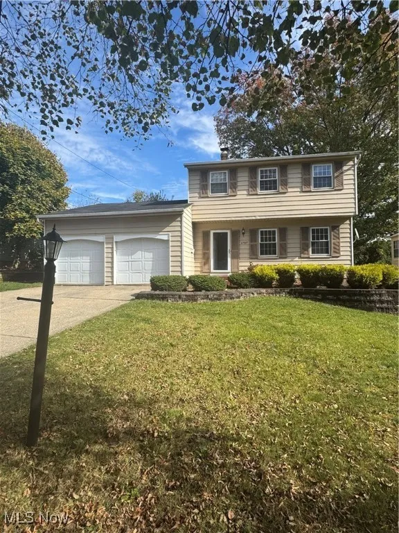 Colonial inspired home featuring driveway, a front lawn, and an attached garage