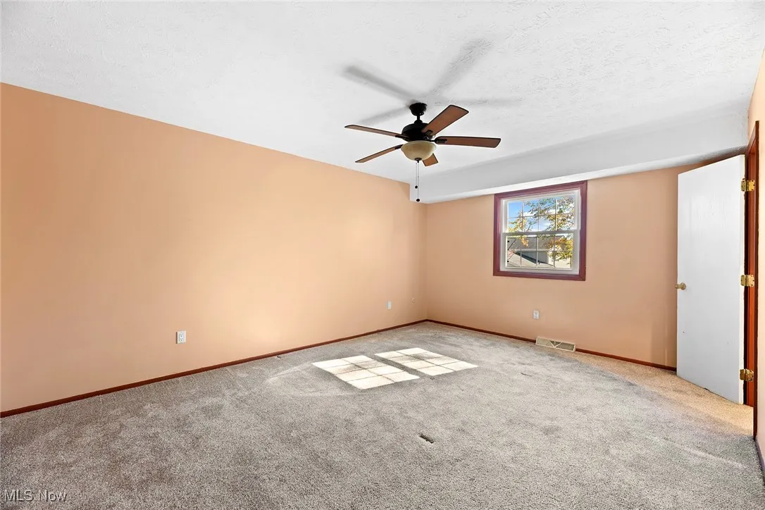 Empty room with a textured ceiling, carpet, and ceiling fan
