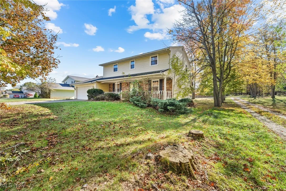 Traditional-style house with a porch, an attached garage, a front yard, brick siding, and driveway