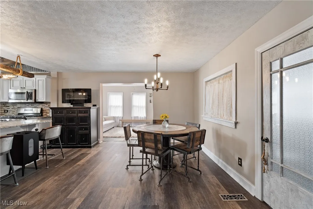 Dining space with dark wood finished floors, a textured ceiling, and a chandelier