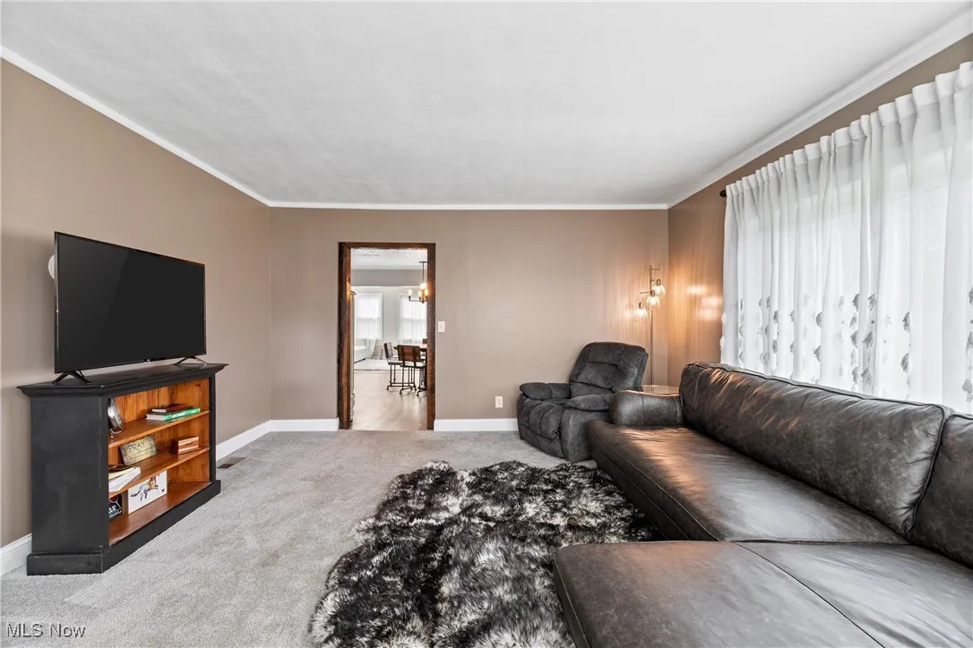 Living room featuring ornamental molding, carpet flooring, and a chandelier
