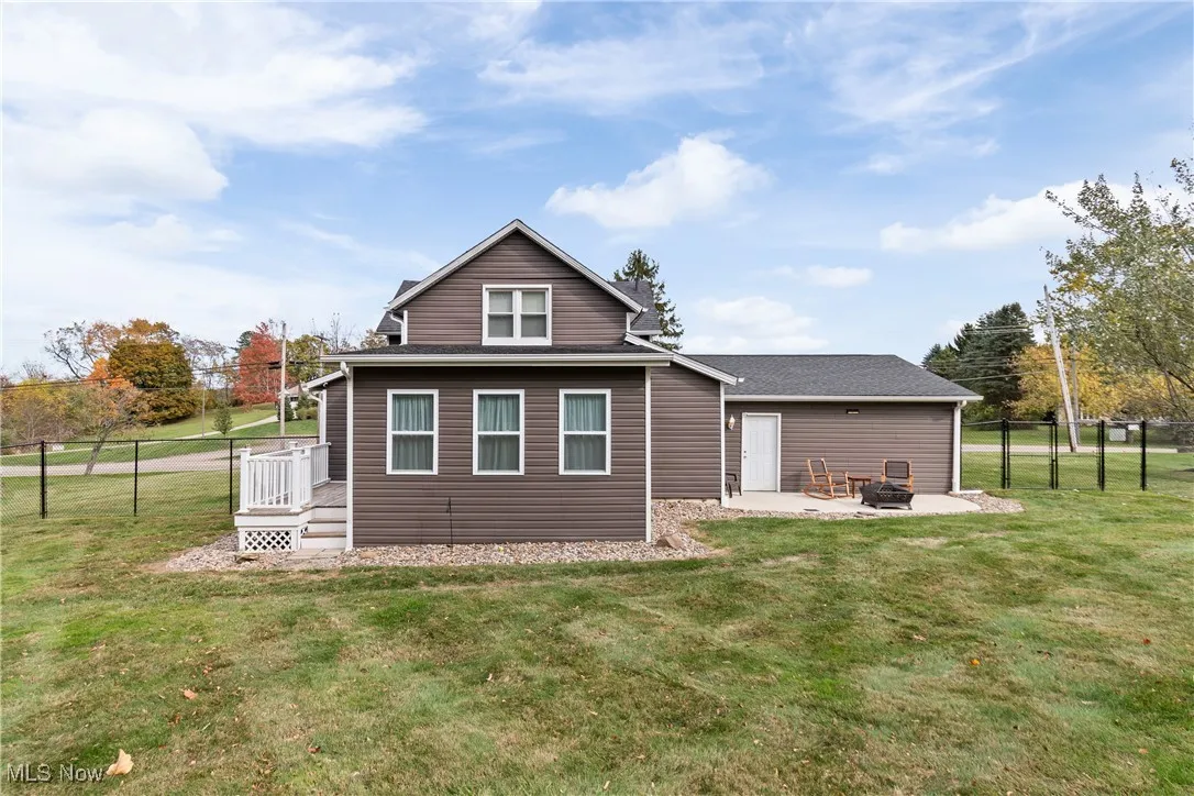 Back of property featuring a fire pit, a patio area, a shingled roof, and a gate