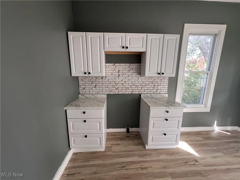 Kitchen featuring light wood-style floors, tasteful backsplash, and white cabinets