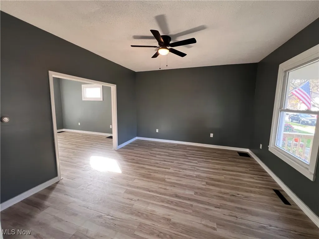 Empty room with light wood-style flooring, a textured ceiling, and ceiling fan