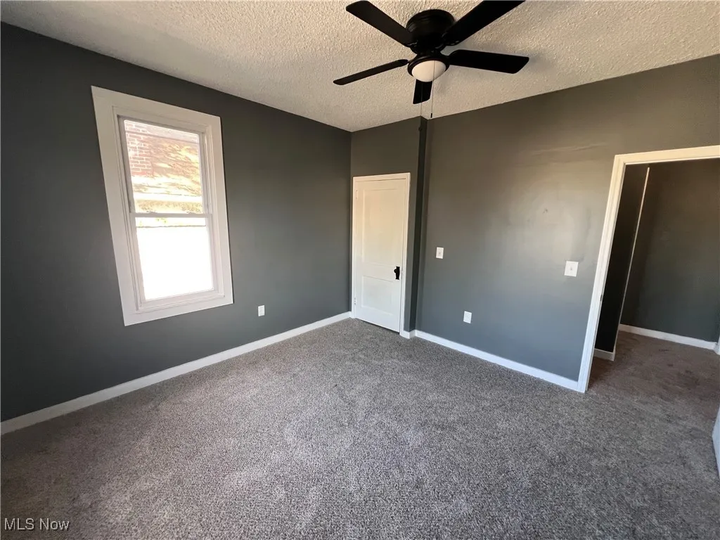 Unfurnished bedroom with a textured ceiling, carpet flooring, and ceiling fan