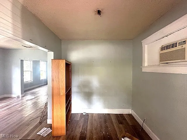 Empty room featuring dark wood-style flooring, a textured ceiling, and a wall mounted AC