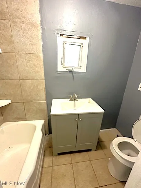 Full bath with light tile patterned floors, vanity, and tile walls