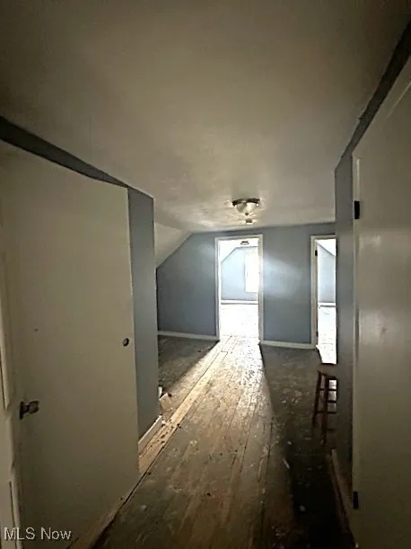 Additional living space with dark wood-style floors and lofted ceiling