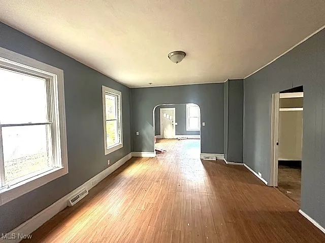 Spare room with arched walkways and wood finished floors